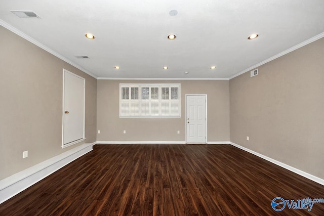 spare room with dark wood-style floors, baseboards, visible vents, and ornamental molding