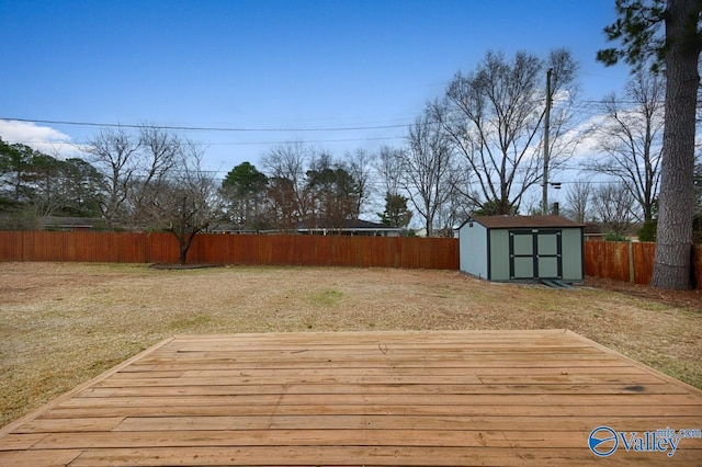 wooden terrace with an outbuilding, a storage unit, a lawn, and a fenced backyard