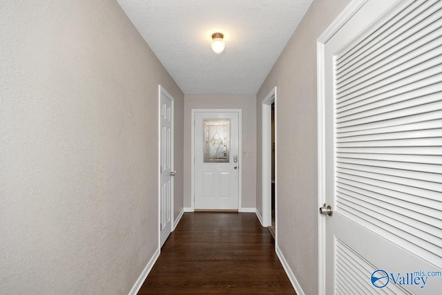 hall with baseboards, dark wood finished floors, and a textured wall