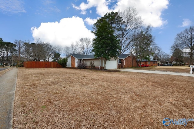 exterior space featuring a garage, driveway, brick siding, and fence