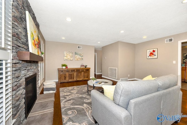 living room featuring a fireplace, wood finished floors, and visible vents