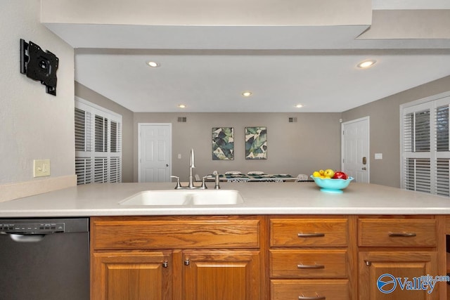 kitchen featuring brown cabinets, dishwashing machine, light countertops, and a sink