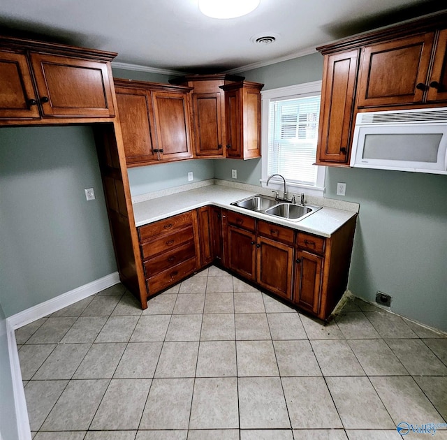 kitchen featuring visible vents, crown molding, white microwave, light countertops, and a sink