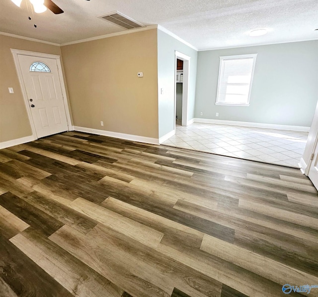 interior space with crown molding, a ceiling fan, wood finished floors, and visible vents