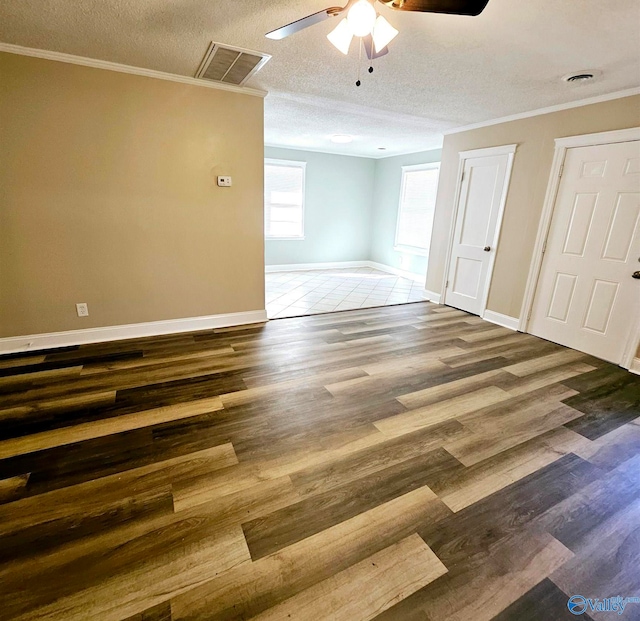 spare room featuring ornamental molding, dark wood-type flooring, a textured ceiling, and ceiling fan