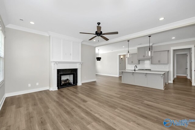 111 Mayapple Trl, Madison, AL 35756 - unfurnished living room with ceiling fan, a tiled fireplace, recessed lighting, baseboards, and wood finished floors