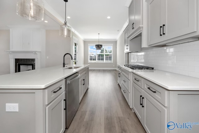 111 Mayapple Trl, Madison, AL 35756 - kitchen featuring a sink, light wood finished floors, stainless steel appliances, baseboards, and decorative backsplash