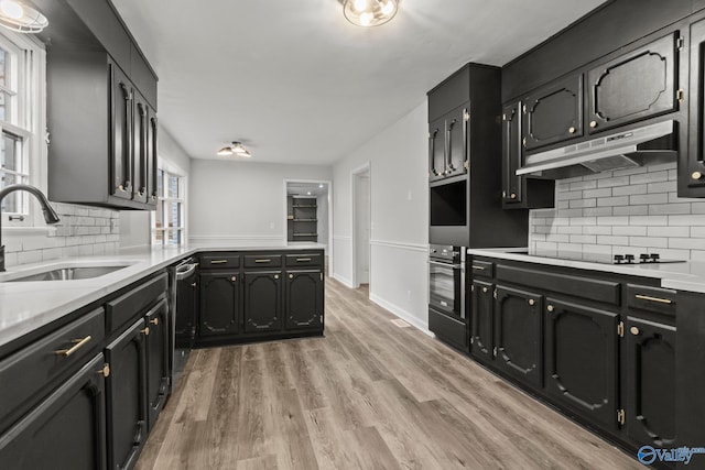 kitchen with light wood-type flooring, appliances with stainless steel finishes, backsplash, and sink