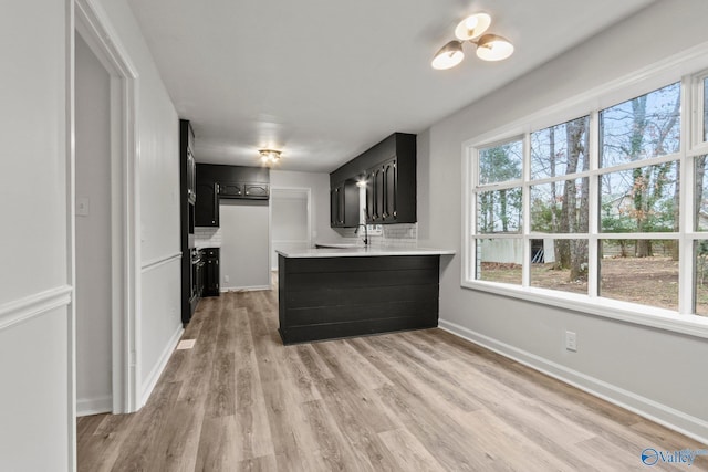 kitchen with kitchen peninsula, tasteful backsplash, and light hardwood / wood-style flooring