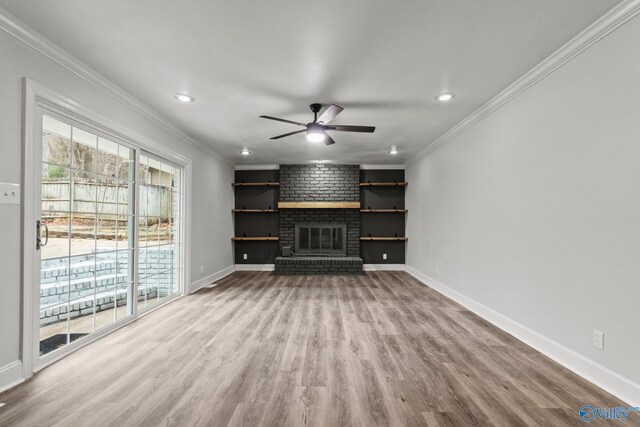 unfurnished living room with hardwood / wood-style floors, ceiling fan, ornamental molding, and a brick fireplace