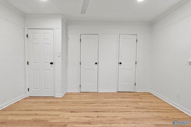 unfurnished bedroom featuring ceiling fan, light wood-type flooring, ornamental molding, and multiple closets