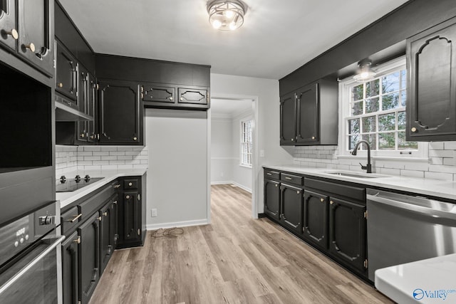 kitchen with decorative backsplash, sink, light hardwood / wood-style floors, and appliances with stainless steel finishes