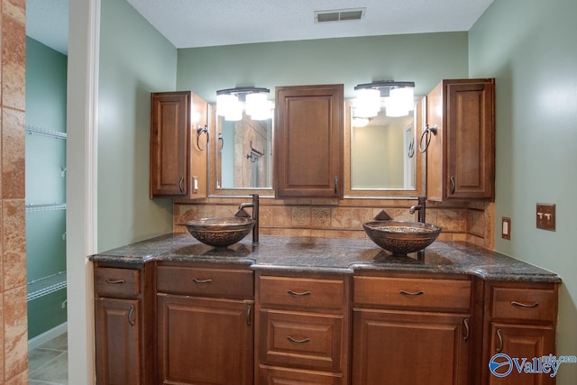 bathroom with tasteful backsplash, visible vents, double vanity, and a sink