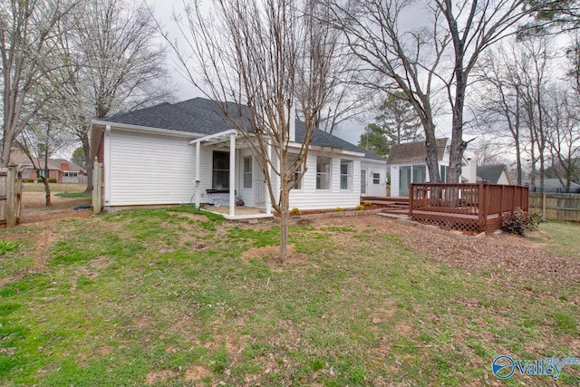 back of house with a shingled roof, a wooden deck, a yard, and fence