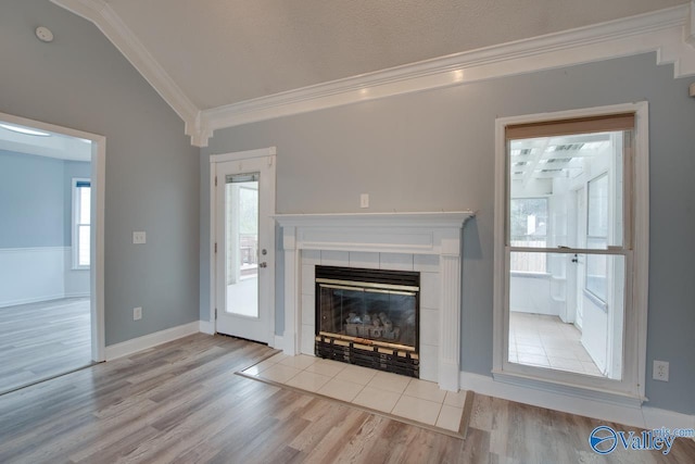 unfurnished living room featuring a tile fireplace, wood finished floors, baseboards, and ornamental molding