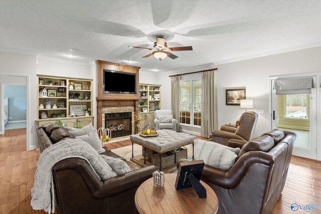 living room with ceiling fan, ornamental molding, light hardwood / wood-style floors, and a textured ceiling