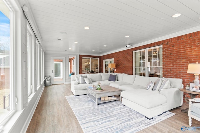 living room featuring ornamental molding, brick wall, and light wood-type flooring