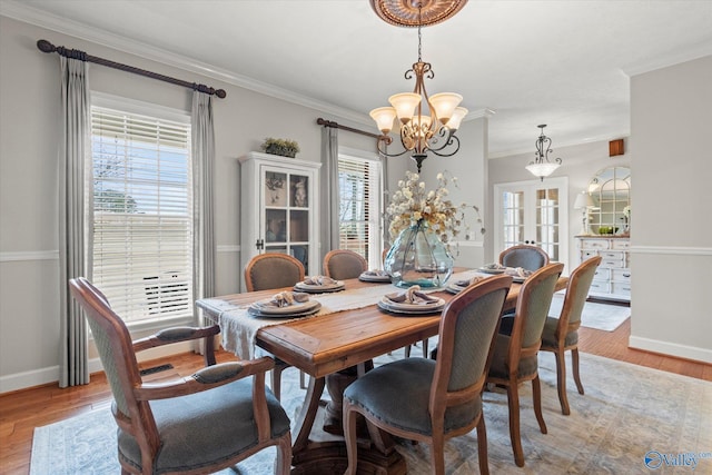 dining room featuring french doors, ornamental molding, light hardwood / wood-style floors, and a notable chandelier