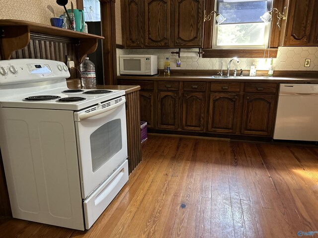 kitchen with sink, light hardwood / wood-style flooring, dark brown cabinets, white appliances, and tasteful backsplash