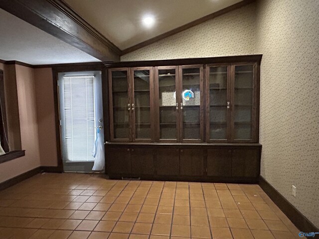 interior space with lofted ceiling, light tile patterned flooring, and ornamental molding