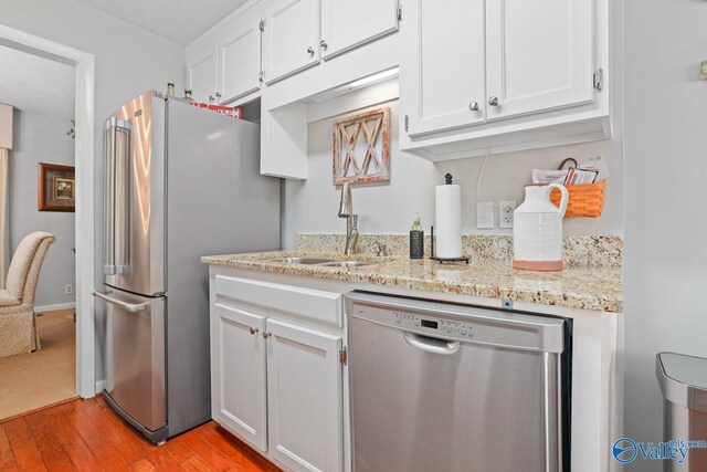 12501 S Shawdee Rd SE, Huntsville, AL 35803 - kitchen featuring appliances with stainless steel finishes, light wood-style flooring, white cabinets, and light stone counters