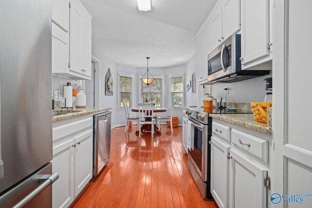 12501 S Shawdee Rd SE, Huntsville, AL 35803 - kitchen with stainless steel appliances, white cabinets, light wood-type flooring, pendant lighting, and baseboards
