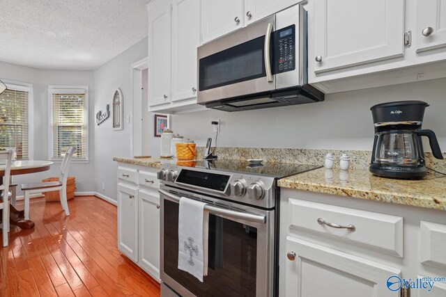 12501 S Shawdee Rd SE, Huntsville, AL 35803 - kitchen featuring stainless steel appliances, white cabinets, light wood-type flooring, a textured ceiling, and light stone counters