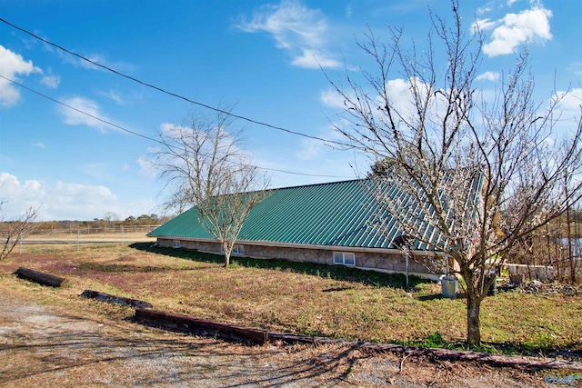 view of side of property featuring metal roof and fence