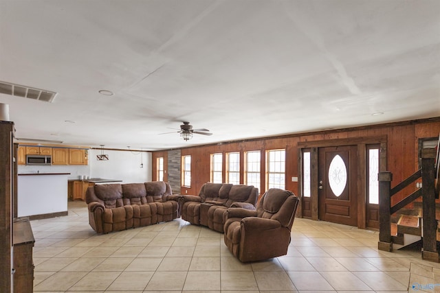 living room with wooden walls, light tile patterned floors, and visible vents