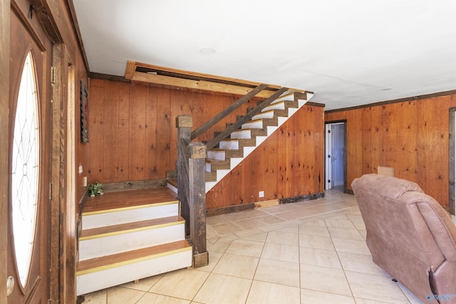 staircase featuring tile patterned floors and wood walls