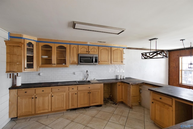 kitchen featuring dark countertops, stainless steel microwave, decorative backsplash, and a sink