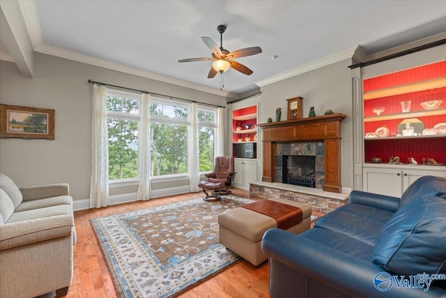 living area featuring wood finished floors, a tiled fireplace, ornamental molding, and ceiling fan