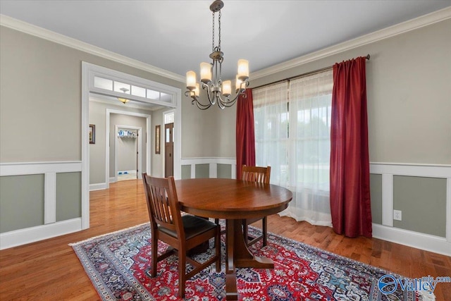 dining space with a chandelier, wood finished floors, and ornamental molding