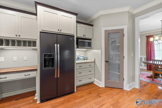 kitchen featuring stainless steel microwave, an inviting chandelier, ornamental molding, refrigerator with ice dispenser, and light wood finished floors