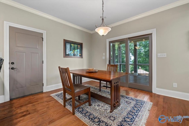 dining space featuring baseboards, ornamental molding, and wood finished floors
