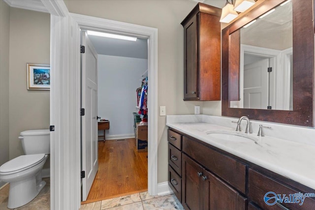 bathroom with toilet, vanity, and baseboards