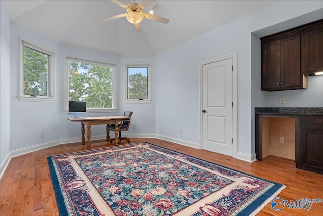 office featuring baseboards, light wood-type flooring, vaulted ceiling, and a ceiling fan