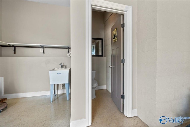 bathroom featuring speckled floor, toilet, and baseboards