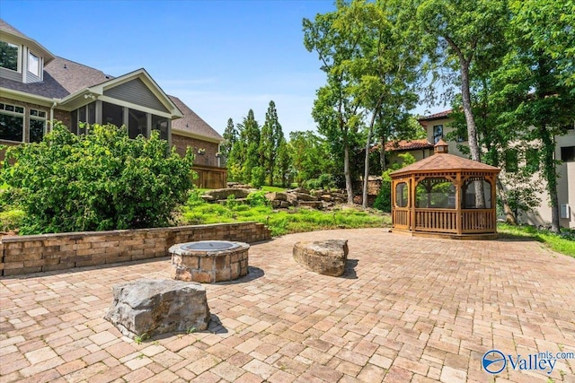 view of patio / terrace featuring an outdoor fire pit, a gazebo, and a sunroom