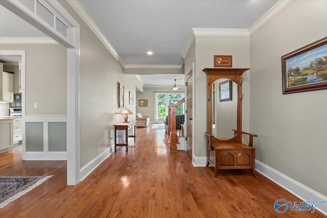 corridor with light wood-type flooring, baseboards, and ornamental molding