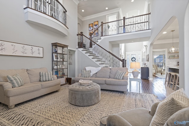 living room featuring hardwood / wood-style floors, a towering ceiling, and ornamental molding