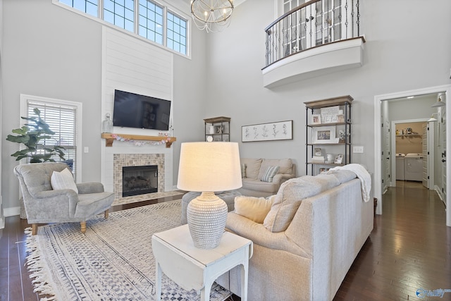 living room with dark hardwood / wood-style flooring, washer and clothes dryer, a tile fireplace, and a high ceiling