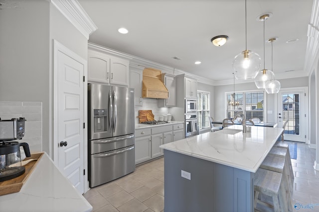 kitchen featuring pendant lighting, an island with sink, ornamental molding, stainless steel appliances, and custom range hood