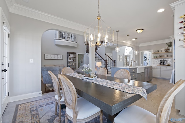 dining area with sink, light tile patterned floors, ornamental molding, and a chandelier