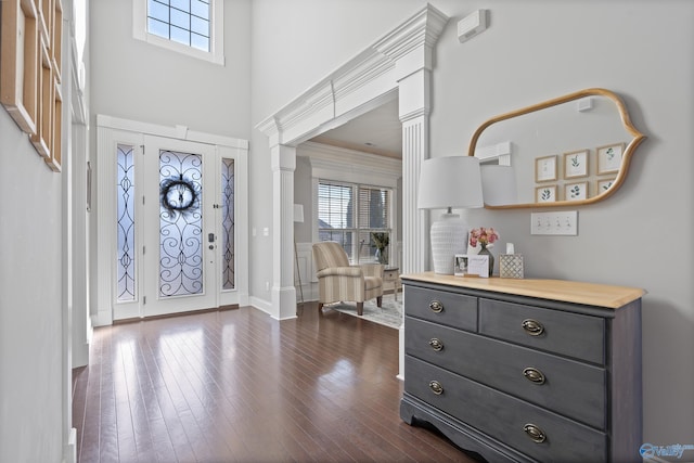 foyer entrance with decorative columns, plenty of natural light, dark hardwood / wood-style floors, and a towering ceiling