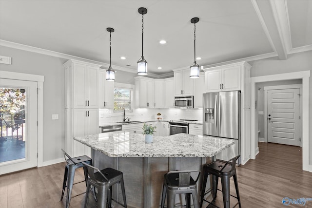 kitchen featuring white cabinets, a center island, stainless steel appliances, a kitchen bar, and a sink