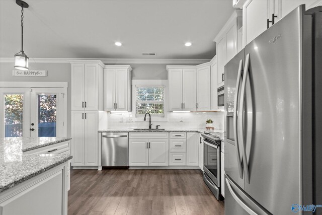 kitchen with light stone countertops, white cabinetry, appliances with stainless steel finishes, and a sink