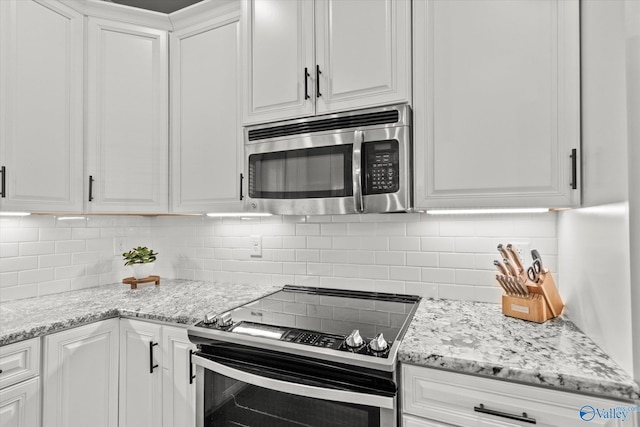 kitchen featuring stainless steel appliances, tasteful backsplash, white cabinetry, and light stone counters