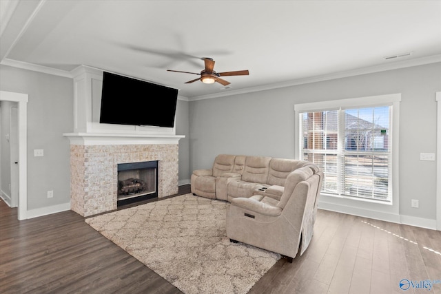 living room featuring baseboards, visible vents, a tile fireplace, dark wood-style flooring, and crown molding