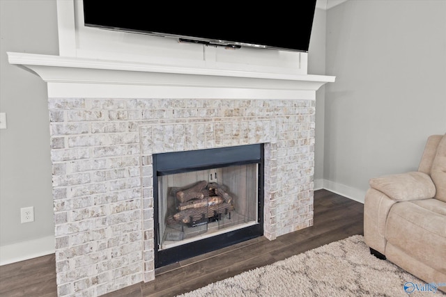 room details featuring a fireplace, baseboards, and wood finished floors